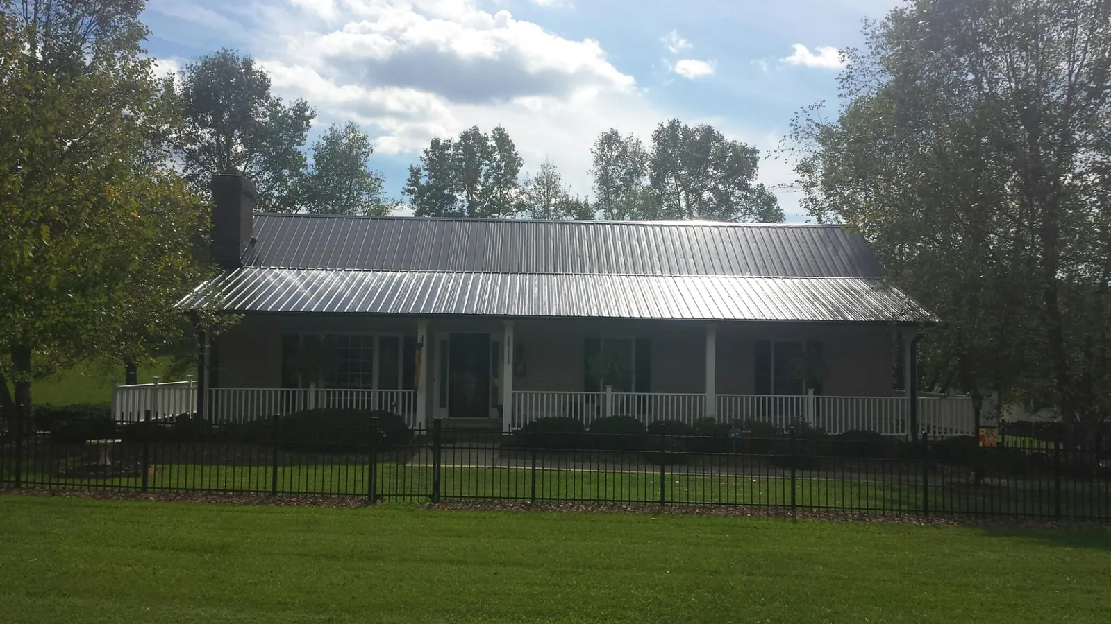 Gray metal roof on a brick ranch with a full width front porch — Gutter Guard Installation work by our crew in Oneida