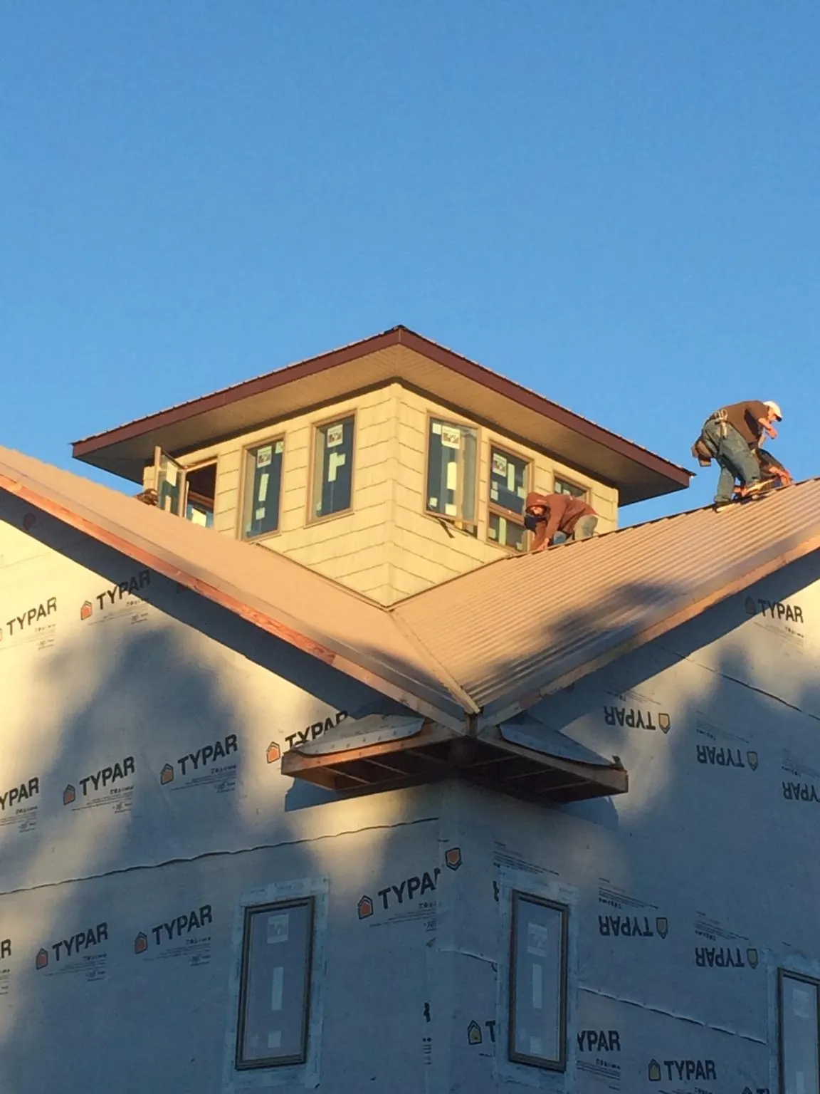 Roofers working around a rooftop cupola on a new metal roof at sunset — Roof Waterproofing in Oneida by Roofing Brothers